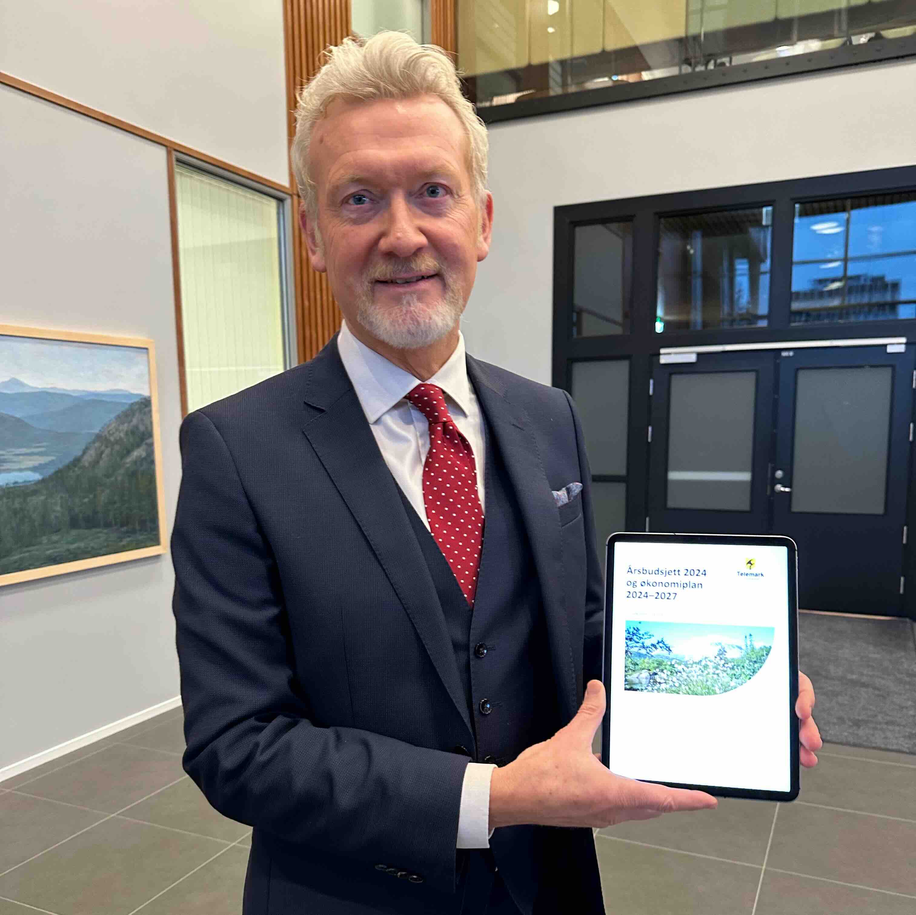 Mann i dress holder opp en ipad