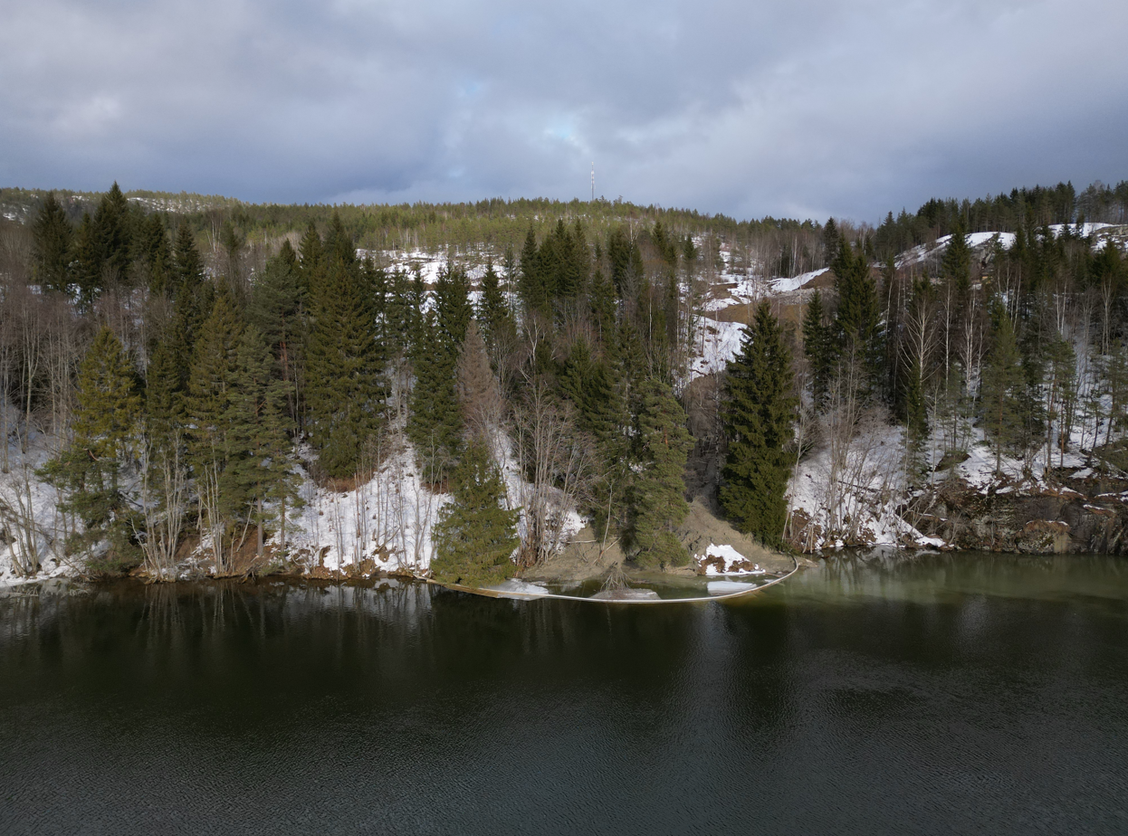 Eidselva synlig i bildets fremkant, anleggsområdet til ny vei i bakgrunnen. Skredløp og siltgardin vises i midten av bildet.