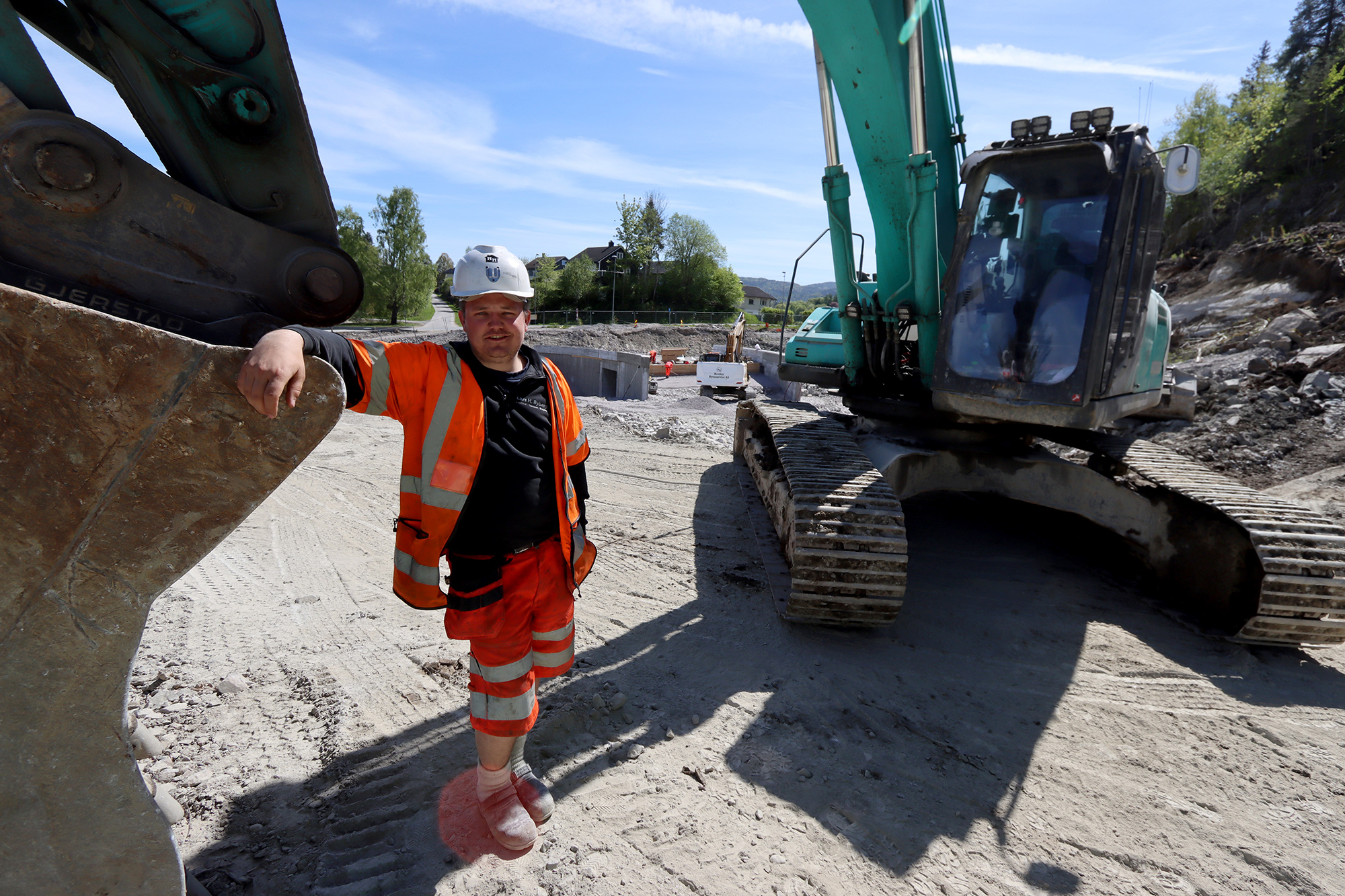 Lærling Emil Øverbø (20) poserer sammen med sin gravemaskin.
