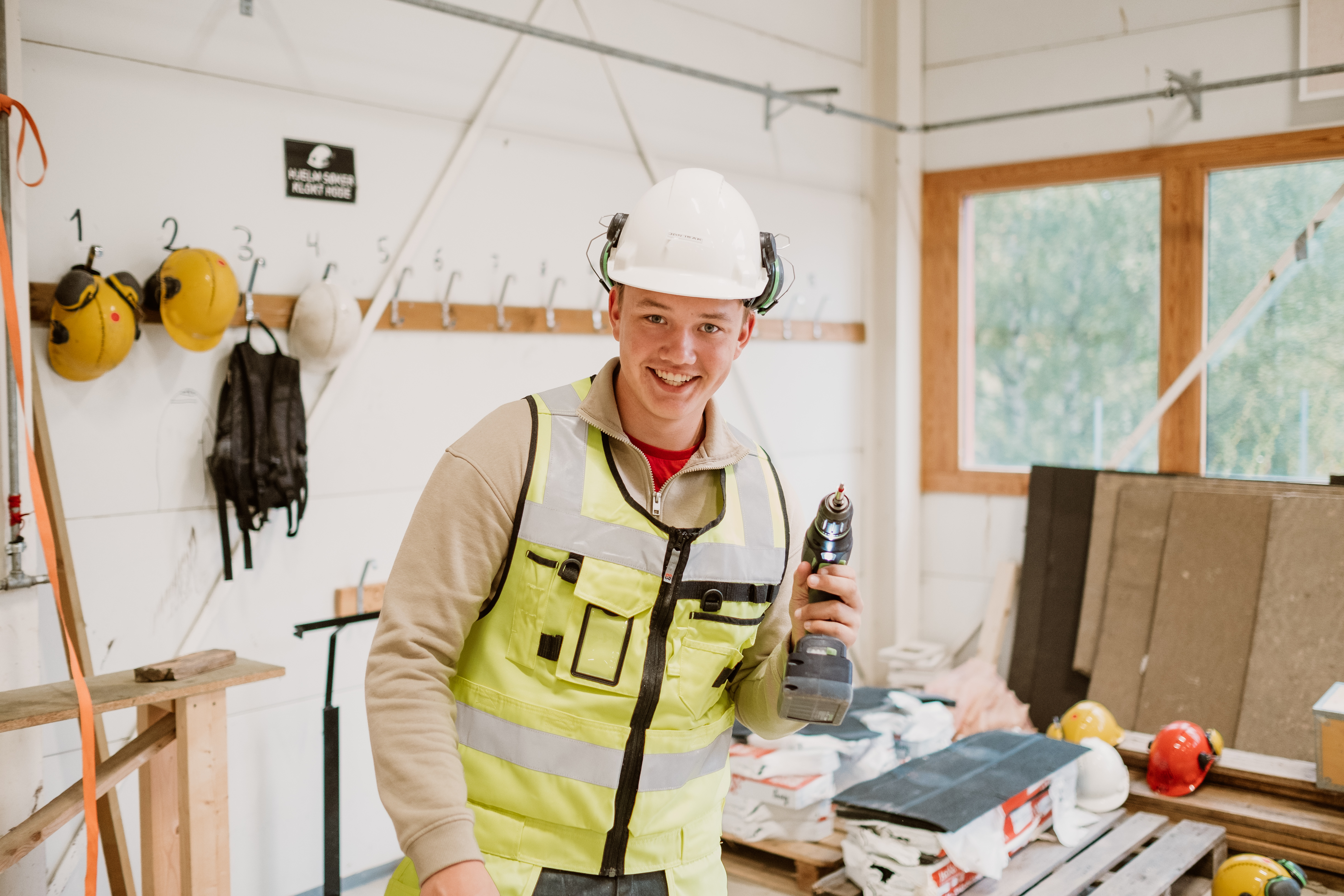 Gutt med drill og utstyr i bygg-verkstedet