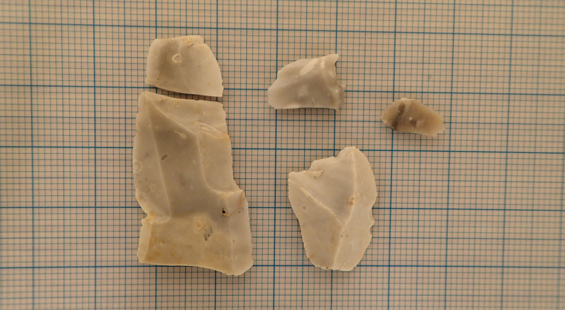 fem flintbiter som ligger på et millimeterpapir