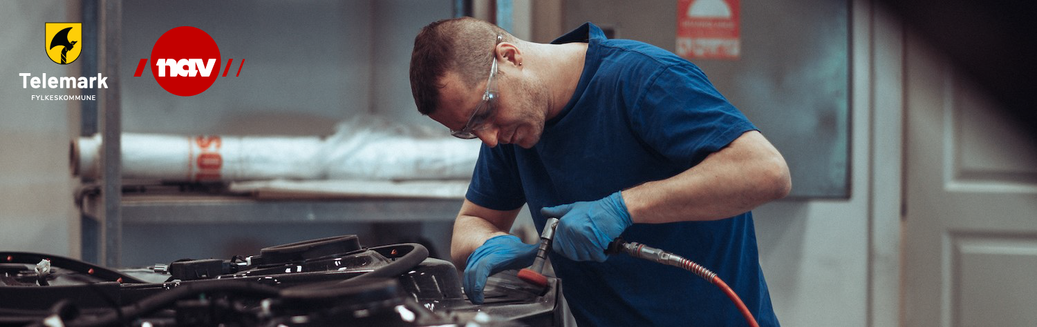 Mann med beskyttelsesbriller som arbeider på veksted.