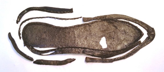 En gammel skosåle som er brun og har noen deler som ligger rundt sålen.