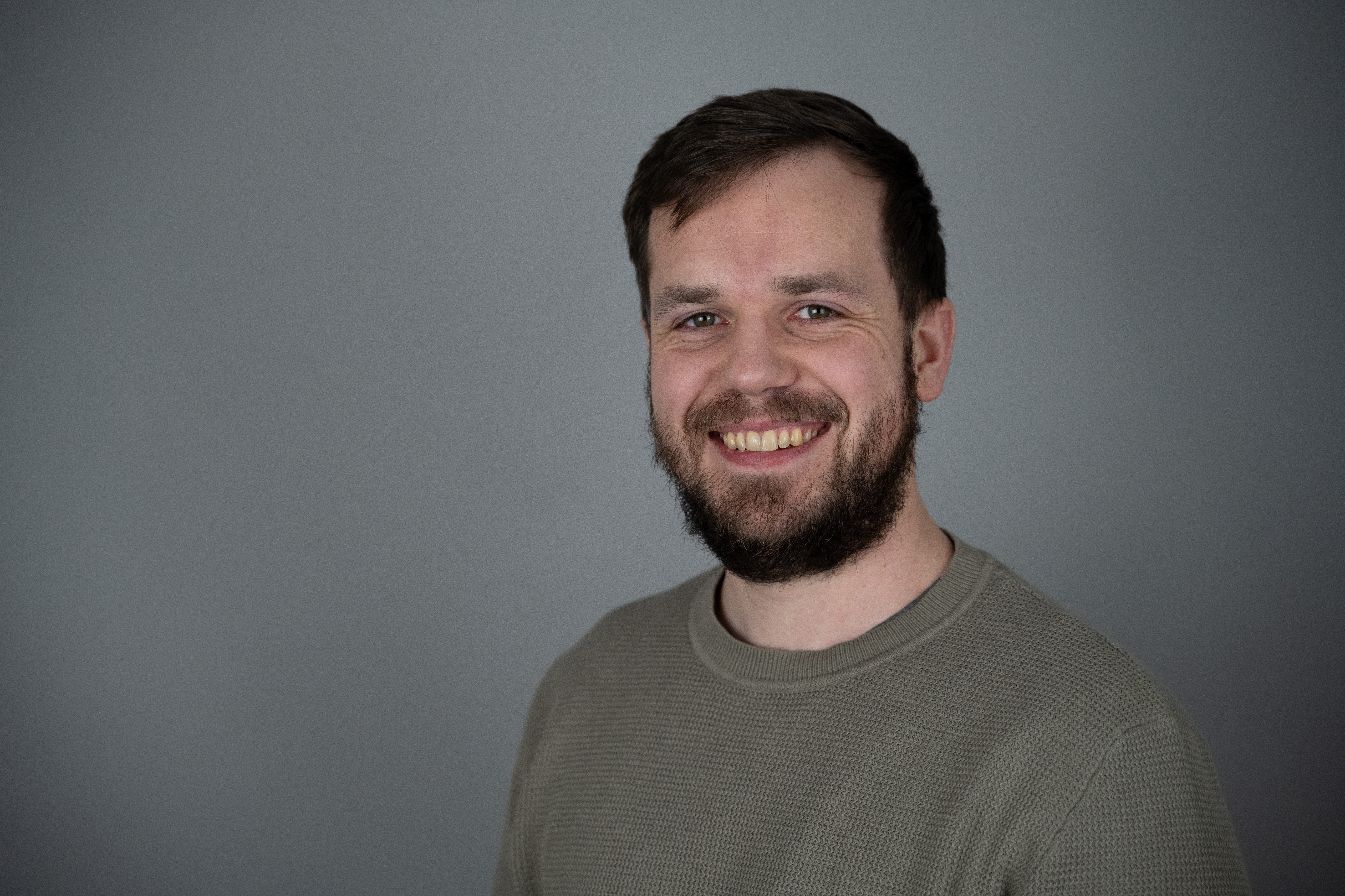 Portrettfoto av en mann med mørkt hår og skjegg.