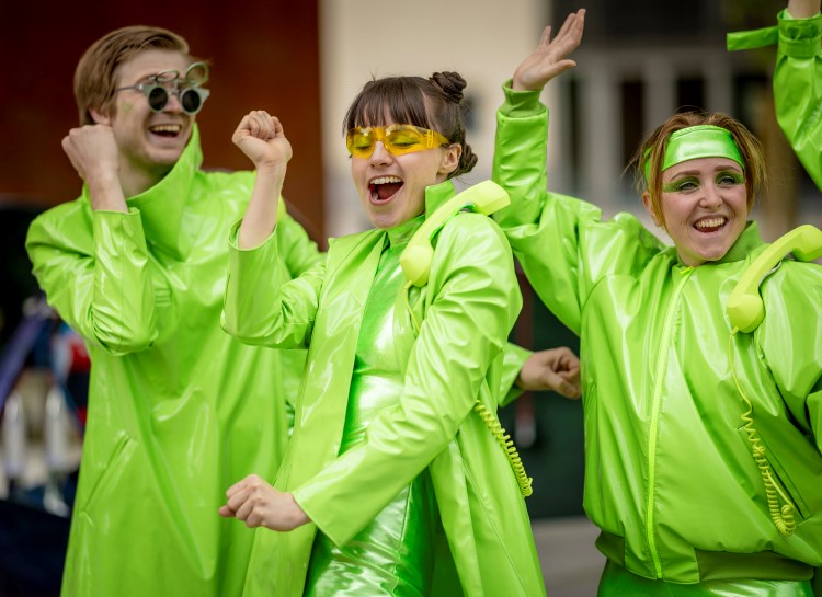 Tre personer kledd i grønn plast jubler og ser rare ut.