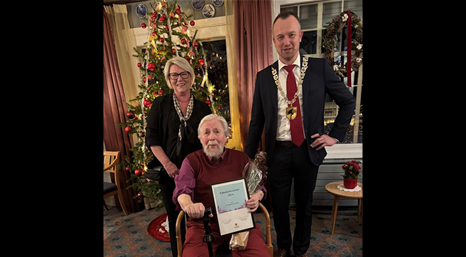 En kvinne og en mann som står på hver sin side av en eldre mann.