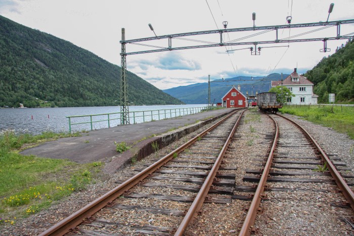 rustne jernbaneskinner med stasjon i bakgrunnen