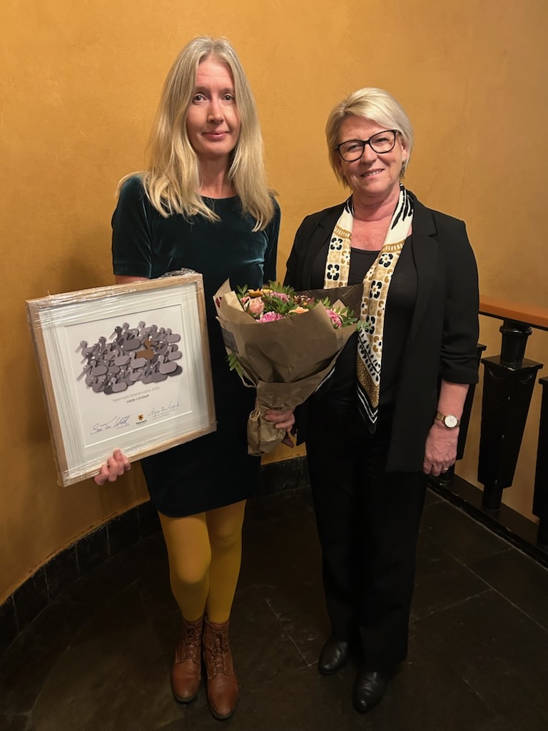 To kvinner som står med et diplom.