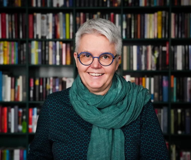 Åsne Midtbø Aas står foran en bokhylle