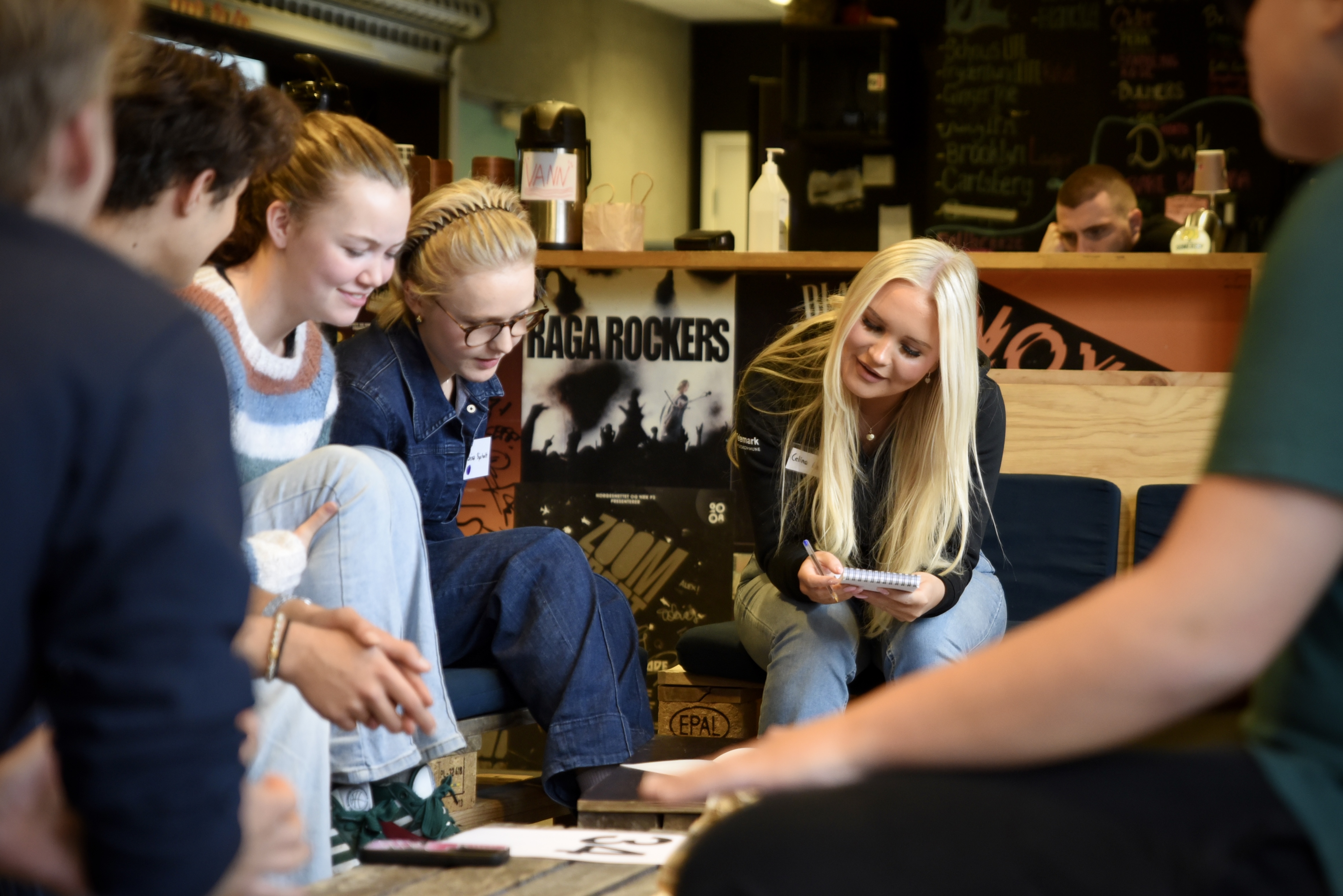 En gruppe ungdommer smiler og fokuserer på felles notat.