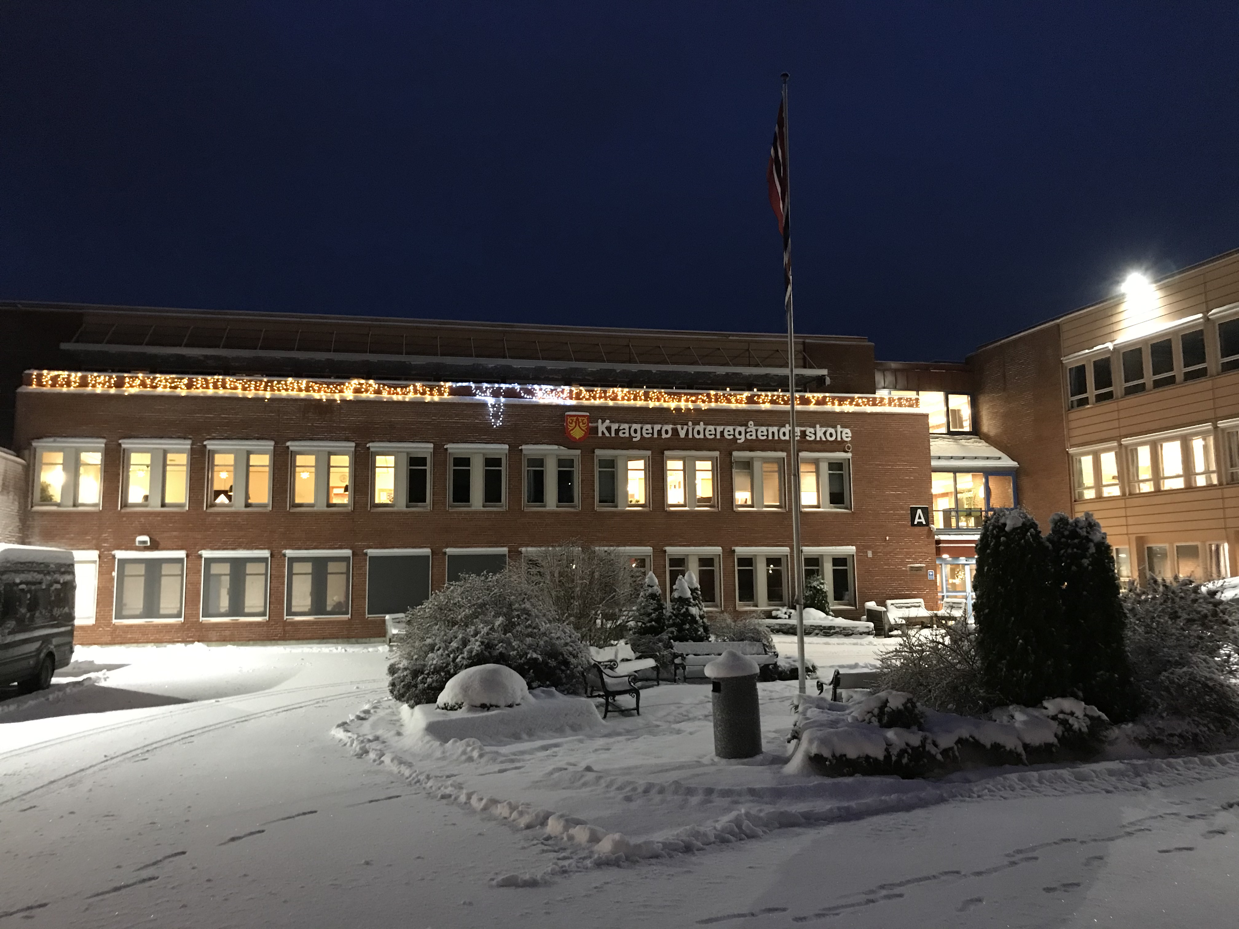 Skolen og skolegården med nysnø og kveldshimmel