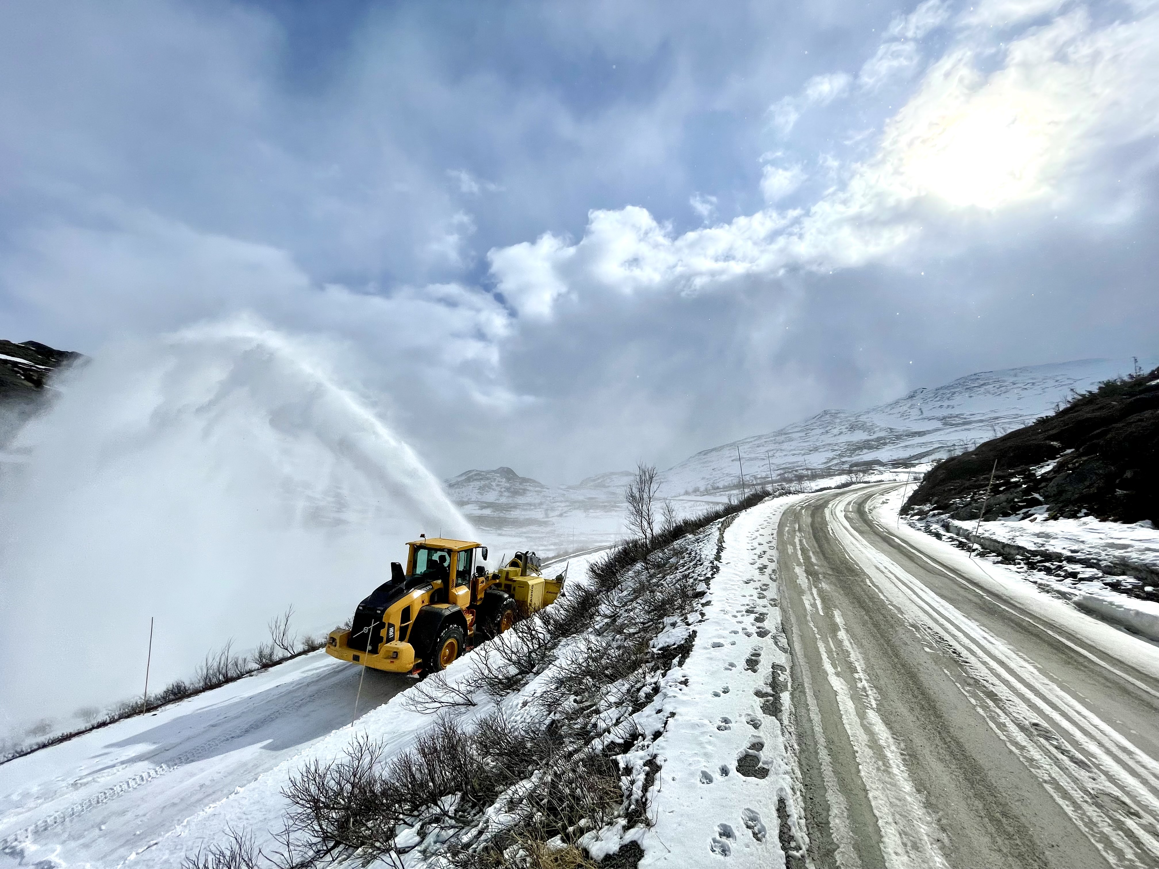 Brøytebil med snøfres jobber seg innover i bildet.